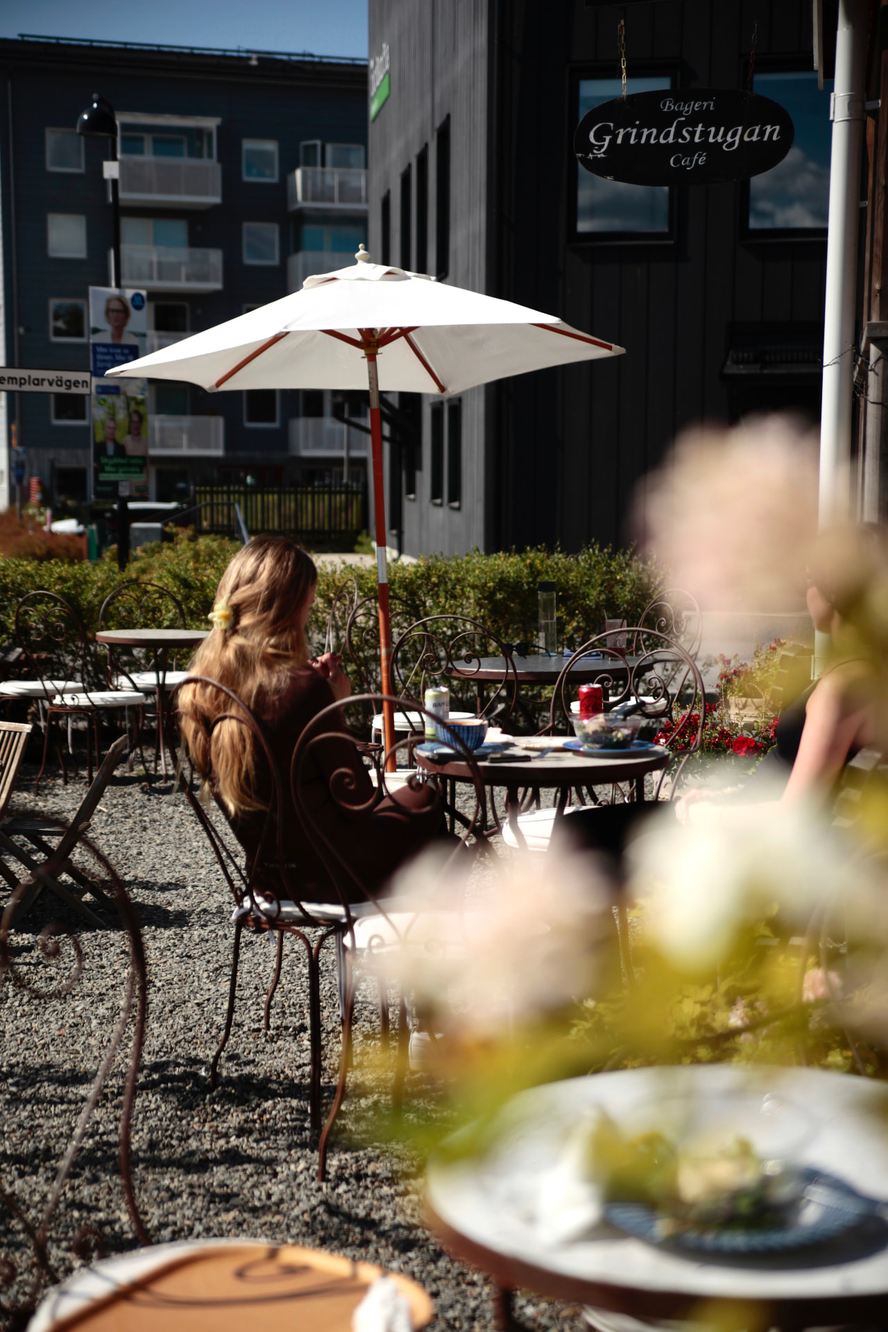 Café Grindstugans soliga uteservering med parasoll och gäster i Tollare